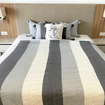 Plaid gris et blanc utilisé comme couverture sur un lit, élégant et confortable