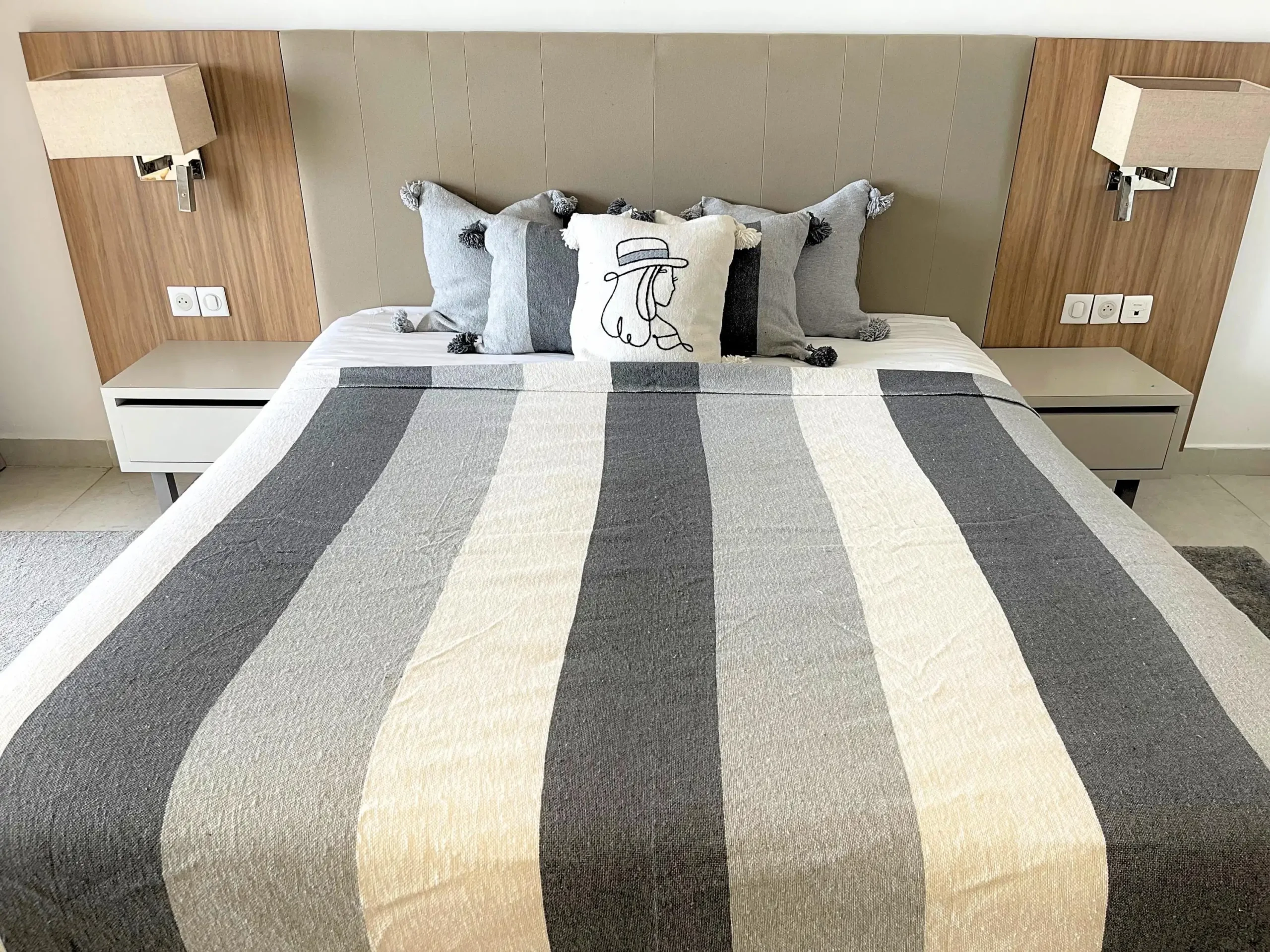 Plaid gris et blanc utilisé comme couverture sur un lit, élégant et confortable